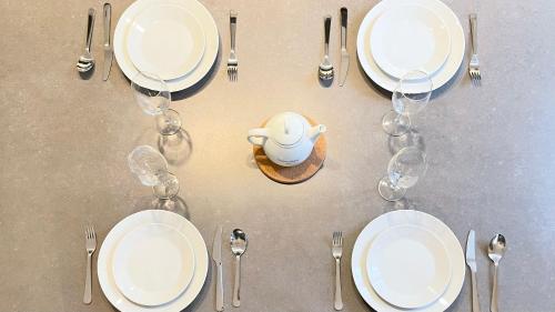 - une table avec des assiettes et des fourchettes blanches et des verres à vin dans l'établissement 107 - Tour Eiffel Appartement luxe 15ème, à Paris