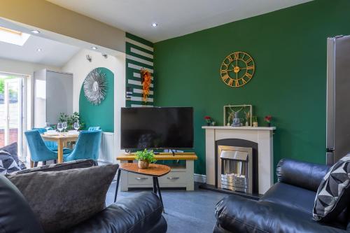 a living room with a green wall with a tv and a fireplace at Smart Stays for Busy Days in Stivichall