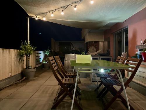 une salle à manger avec une table et des chaises vertes dans l'établissement La londe les Maures Location saisonnière Grand Toit-Terrasse, à La Londe-les-Maures