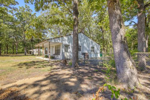 a white barn with trees in front of it at 5 Mi to Sardis Lake Pet-Friendly Cabin Rental in Batesville