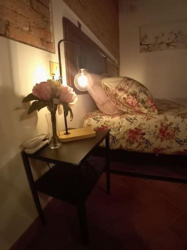 a bedroom with a table with a vase of flowers and a bed at Casa Torre Borgo dei Borghi in Peccioli