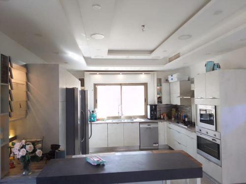 eine Küche mit weißen Schränken und einem großen Fenster in der Unterkunft Vienna Villa for you in Al Qasţal