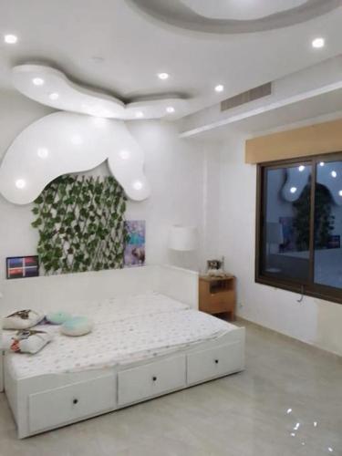 a bedroom with a white bed and a tv at فيلا وشاليه فيينا in Al Qasţal