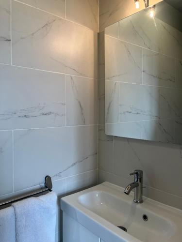 une salle de bain blanche avec un lavabo et un miroir dans l'établissement Maison Colombes, à Colombes