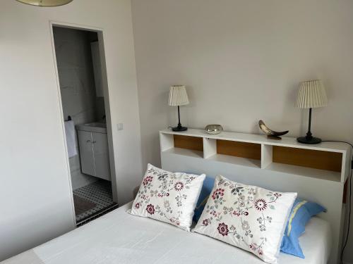 une chambre avec un lit avec deux oreillers et un miroir dans l'établissement Maison Colombes, à Colombes