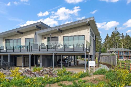 a house with a balcony with chairs on it at Beachfront Villa #14 at The Beach House in Campbell River