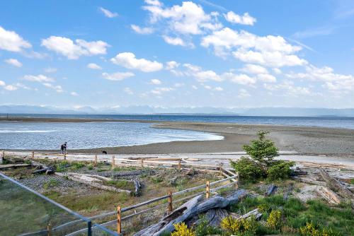 a person walking on a beach near the water at Beachfront Villa #14 at The Beach House in Campbell River