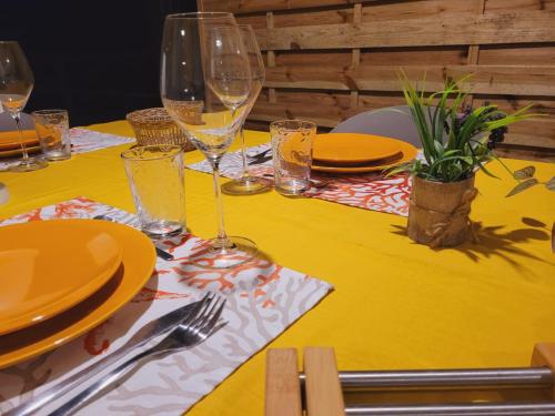 a yellow table with plates and wine glasses on it at MY SWEET HOME Location - Feel Unique, Stay Unique in Faaa