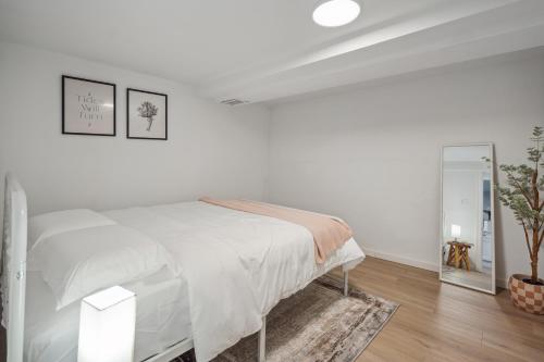 a white bedroom with a bed and a mirror at Spacious 5B2B home 5 min to airport with AC, Game Room, WiFi, Parking in SeaTac