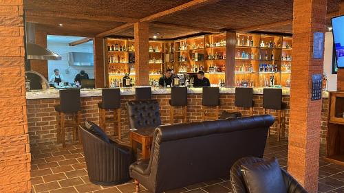 a bar in a restaurant with leather chairs at Le Suisse Spa in Santa Lucía Milpas Altas