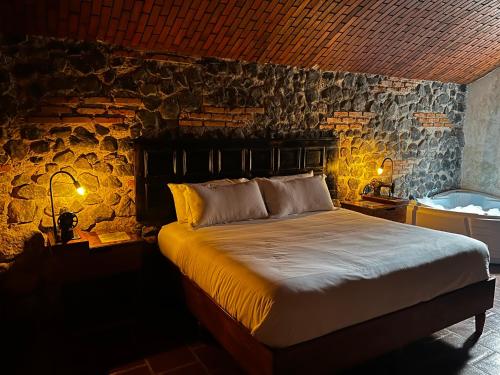 a bedroom with a bed and a stone wall at Le Suisse Spa in Santa Lucía Milpas Altas