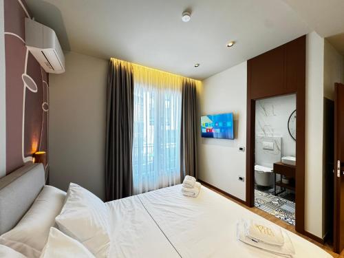 a bedroom with a large white bed and a bathroom at Villa Noem in Tirana