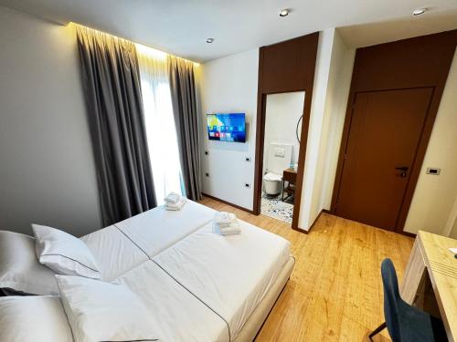 a hotel room with a white bed and a television at Villa Noem in Tirana