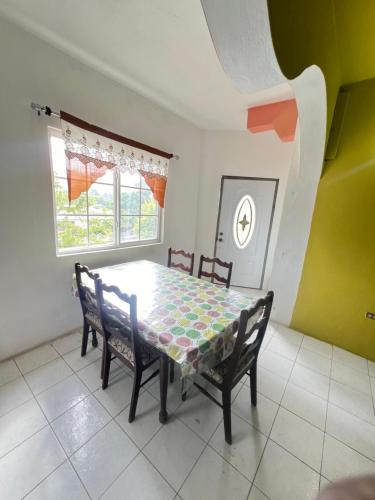 a dining room with a table and chairs and a window at Cozy Family Inn in Port Antonio