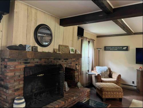 a living room with a brick fireplace and a chair at Admiral Peary Inn in Fryeburg
