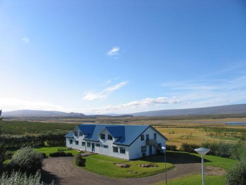 a white house with a blue sky at Eyjólfsstadir Guesthouse in Egilsstaðir