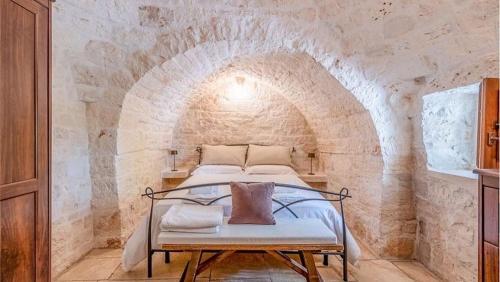 a bedroom with a bed in a stone wall at Trullo Matilde in Martina Franca