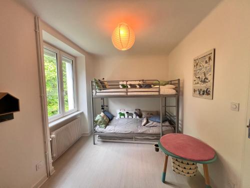 Cette petite chambre comprend des lits superposés et une table. dans l'établissement Sublime maison familiale refaite à neuf Quartier très calme verdoyant, à Plobannalec-Lesconil