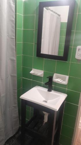 a green tiled bathroom with a sink and a mirror at MOVISTAR ARENA confort in Buenos Aires