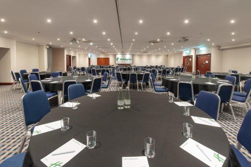 a conference room with black tables and blue chairs at Holiday Inn - Glasgow Airport by IHG in Paisley