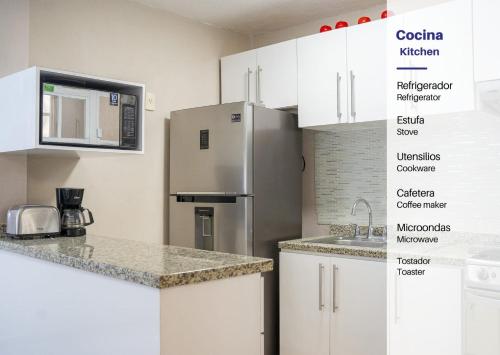 a kitchen with white cabinets and a stainless steel refrigerator at New Acapulco Retreat Garden Pool & Gym in Acapulco