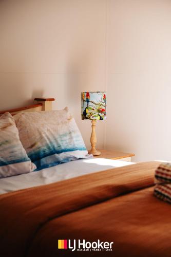 a bedroom with a bed and a lamp on a table at Iluka Calling in Iluka