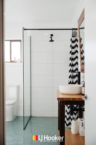 a bathroom with a glass shower door and a sink at Iluka Calling in Iluka