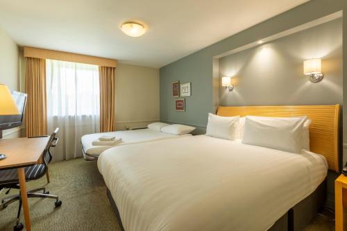 a hotel room with two beds and a desk at Holiday Inn Brentwood by IHG in Brentwood