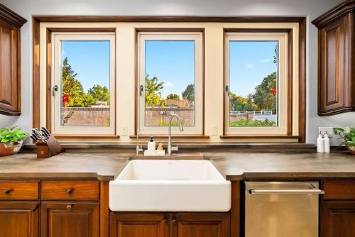 a kitchen with a white sink and three windows at Villa Allegria Luxury Retreat in Templeton