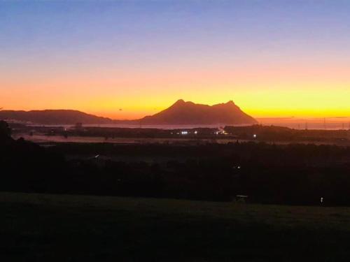 a sunset with a mountain in the background at Moko Hiwi Escape Ruakākā- Sea View Home in Ruakaka