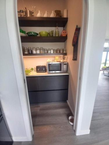 a hallway with a kitchen with a microwave on a counter at Moko Hiwi Escape Ruakākā- Sea View Home in Ruakaka