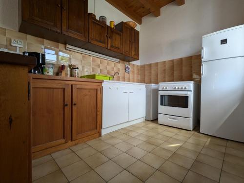 une cuisine avec des armoires en bois et un réfrigérateur blanc dans l'établissement Charmant Gîte en Pierre avec 3 Chambres, Cour et Proximité Activités, Pinols - FR-1-582-252, à Pinols