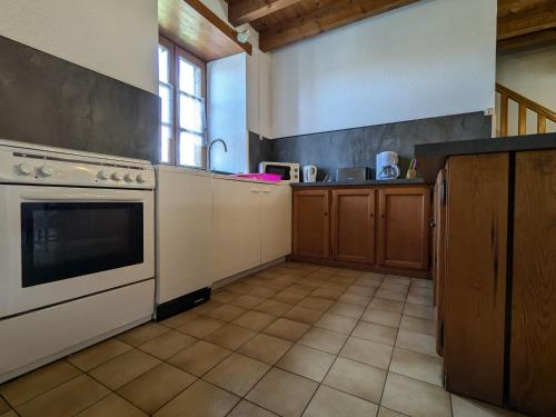 a kitchen with a white stove and a sink at Gîte en pierres avec cour et 3 chambres, au cœur d'un village proche de Langeac - FR-1-582-233 in Pinols