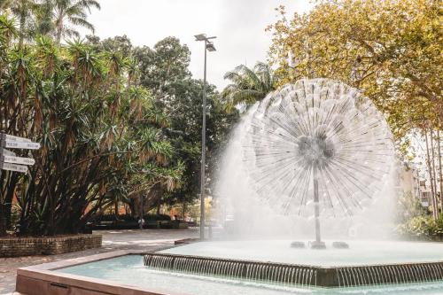 a fountain in a park with a parasol at Holiday Inn Sydney Potts Point in Sydney