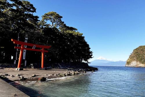 a red torii gate on the shore of a body of water at CalmbasePORT 西伊豆戸田港 Heda in Toda