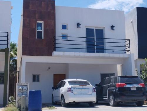 two cars parked in a parking lot in front of a house at Hermosa casa a 5 minutos del consulado Americano, cuenta con 3 recamaras, sistema de refrigeración y calefacción in Ciudad Juárez