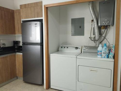 a small kitchen with a refrigerator and a washer at Hermosa casa a 5 minutos del consulado Americano, cuenta con 3 recamaras, sistema de refrigeración y calefacción in Ciudad Juárez