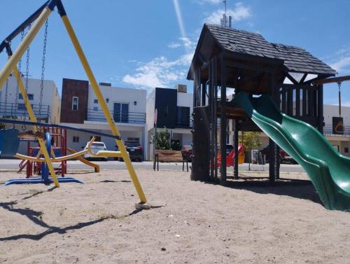 a playground with a slide and swings at Hermosa casa a 5 minutos del consulado Americano, cuenta con 3 recamaras, sistema de refrigeración y calefacción in Ciudad Juárez