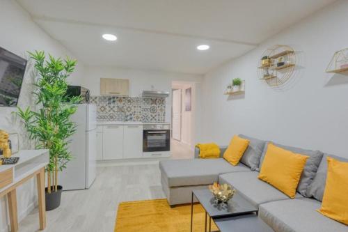 un salon avec un canapé gris et des coussins jaunes dans l'établissement Lux Suite Lorenzo, à Livry-Gargan