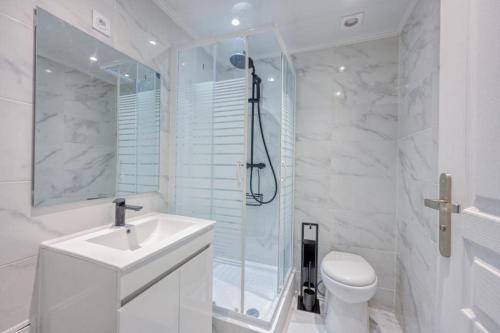 une salle de bain blanche avec un lavabo et une douche dans l'établissement Lux Suite Lorenzo, à Livry-Gargan