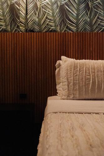 a bed with a white pillow and a wooden wall at Cris Hotel in Florianópolis