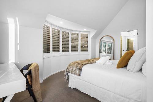 a white bedroom with a bed and a mirror at Overdale Oasis in Christchurch