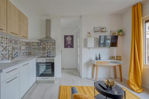 une cuisine avec des armoires blanches et une table dans une pièce dans l'établissement Lux Suite Eliana, à Livry-Gargan