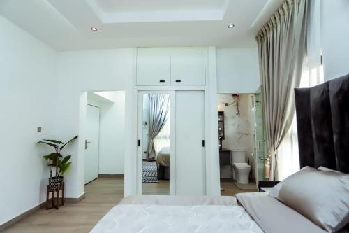 a white bedroom with a white bed and a bathroom at Lush apartment with private rooftop bar Lakeside in Ashalebotwe