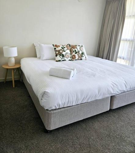 a large bed in a bedroom with a lamp on a table at Central Shepparton Apartment 13 in Shepparton