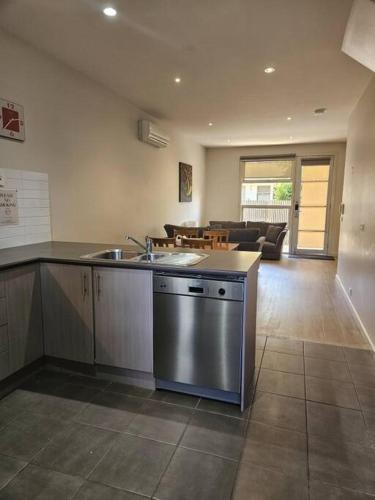 a kitchen with a sink and a living room at Central Shepparton Apartment 13 in Shepparton