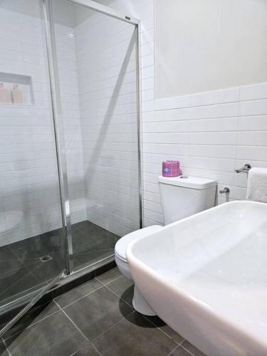 a white bathroom with a shower and a toilet at Central Shepparton Apartment 13 in Shepparton
