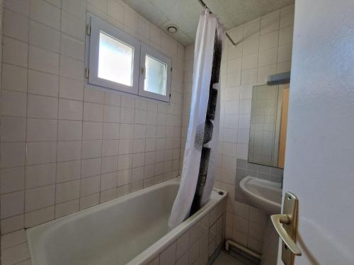 une salle de bain avec une baignoire, un lavabo et une fenêtre dans l'établissement Terraced House in Beg Meil near Sandy Beaches, à Fouesnant