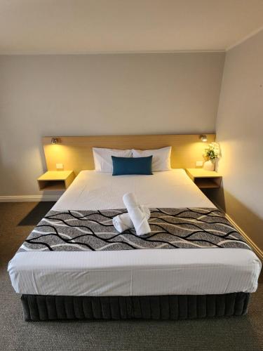 una camera da letto con un grande letto bianco con due comodini di Country Gardens Motel a Coonabarabran