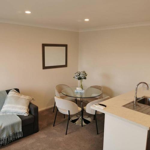 a living room with a table and a couch at Comfort and Peace at The Lakes in Tauranga